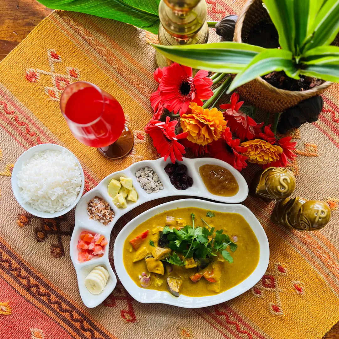 Culinary dish with a side of rice and garnishes on a decorative tablecloth.