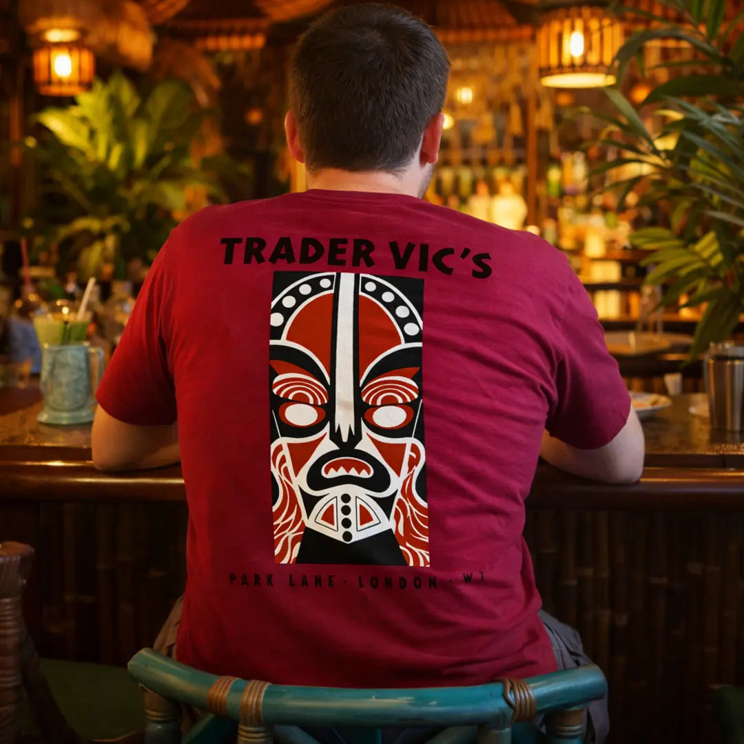 Person wearing a red 'Trader Vic's' t-shirt in a bar setting