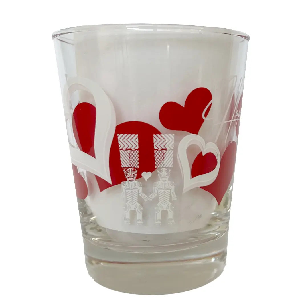 A clear glass with red heart and white silhouette designs, likely representing a Valentine's Day themed drinkware item.