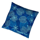 A square blue throw pillow featuring a white tropical floral and leaf pattern, with the brand name 'TRADER VICKS' printed in white near the bottom corner, set against a plain white background.