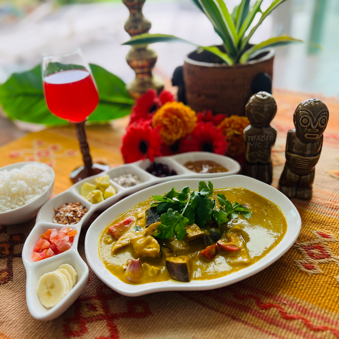 Plated dish of curry with garnishes on a table setting with decorative elements.