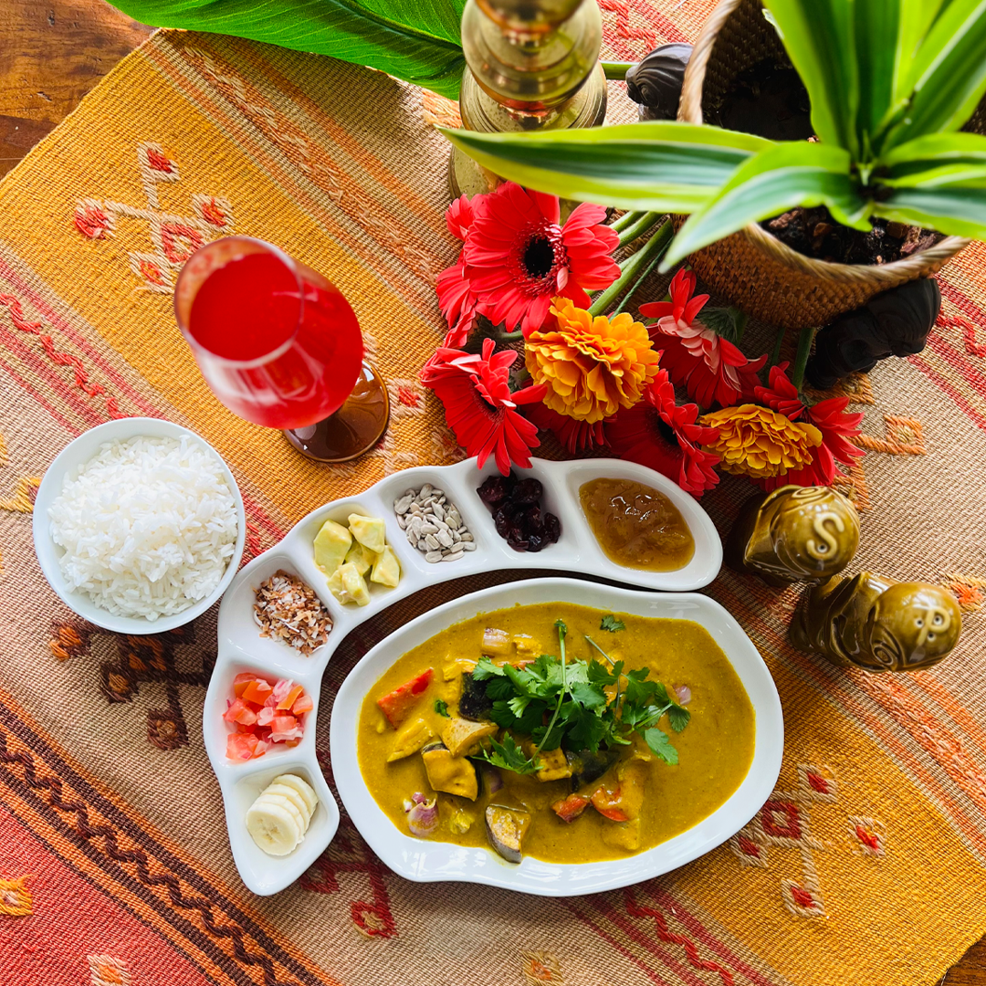 Culinary dish with a side of rice and garnishes on a decorative tablecloth.