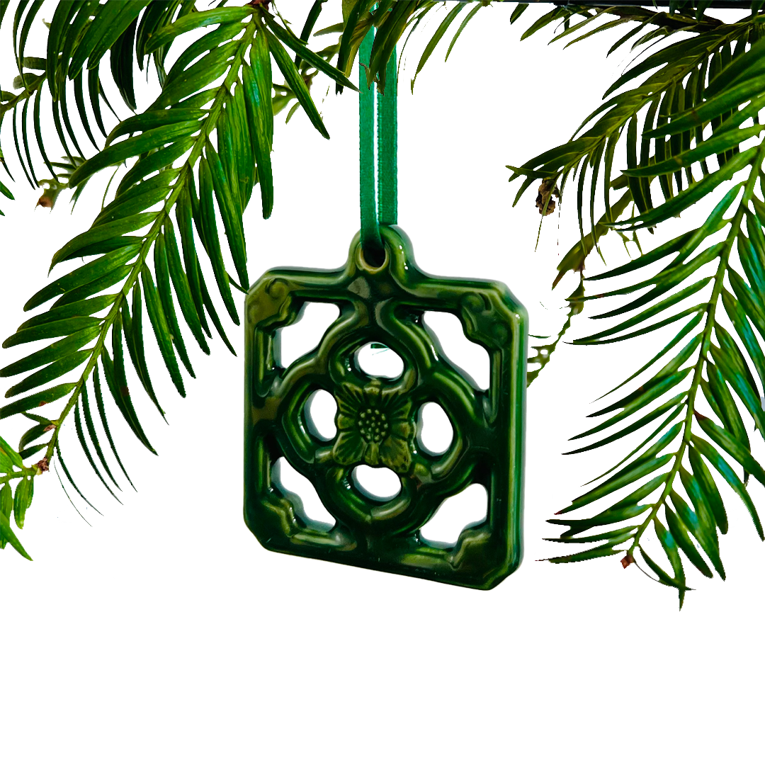 Green decorative ornament hanging from a branch with green leaves.