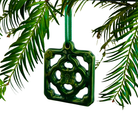 Green decorative ornament hanging from a branch with green leaves.