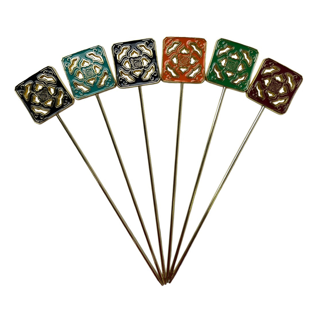 Set of six decorative stick pins with square designs on a white background