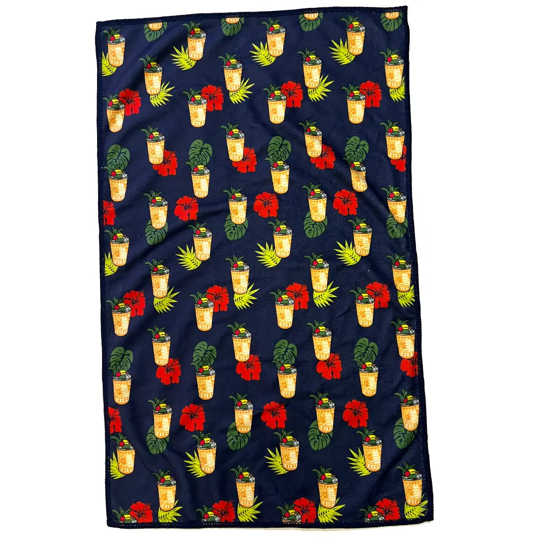 Navy blue towel with tropical pattern featuring drinks, flowers, and leaves.