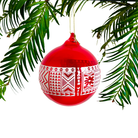 Red Christmas ornament with white patterns hanging on a green branch