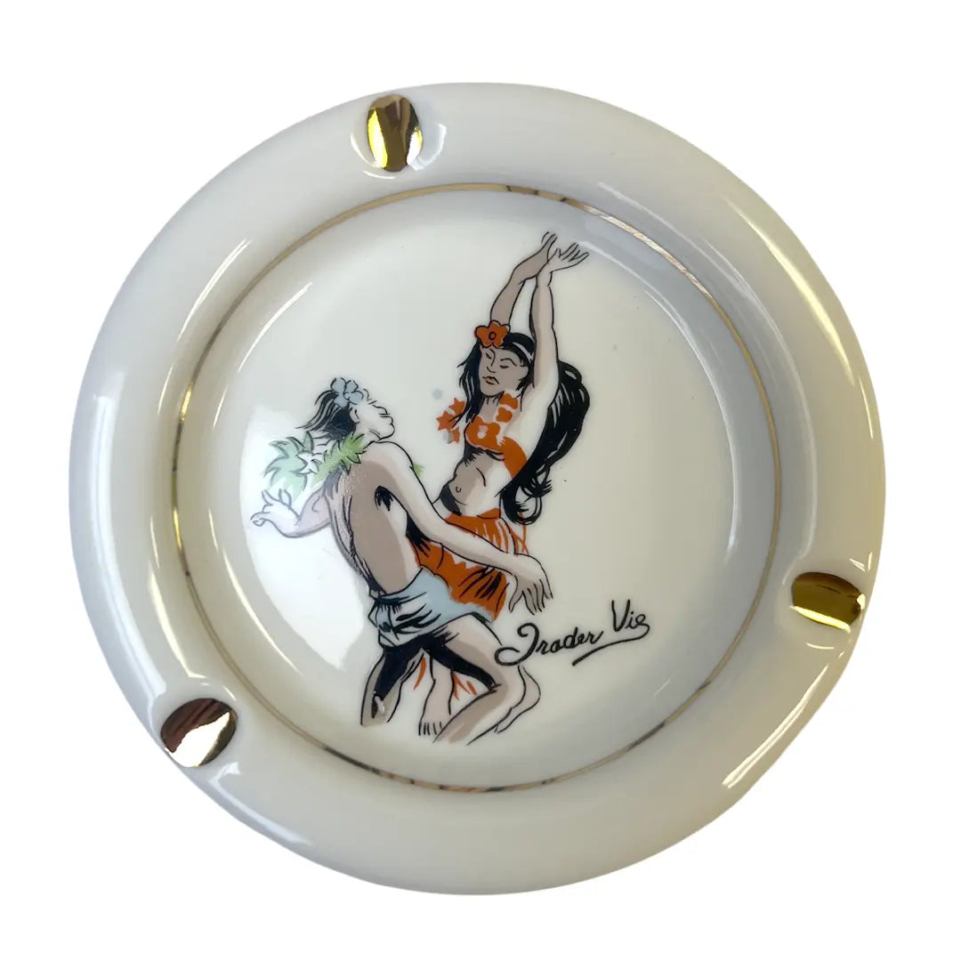 A round ceramic ashtray with a glossy cream-white glaze, featuring a hand-painted illustration of Trader Vic's vintage cocktail menu scene.