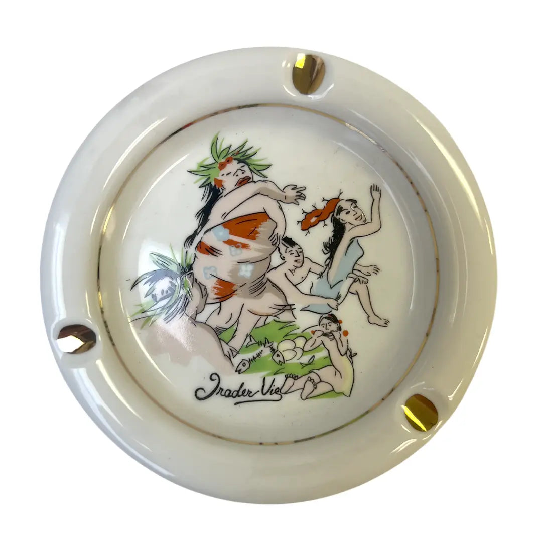 A round ceramic ashtray with a glossy cream-white glaze, featuring a hand-painted illustration of Trader Vic's vintage cocktail menu scene.