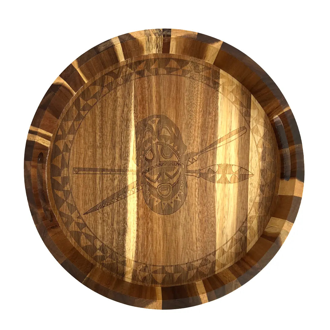 A round wooden serving tray with a hand-tooled shield and spear motif in the center, featuring a striped natural wood pattern around the rim, shown on a solid white background.